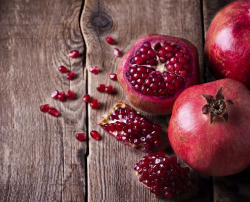 Some Red Pomegranates On Old Wooden Table