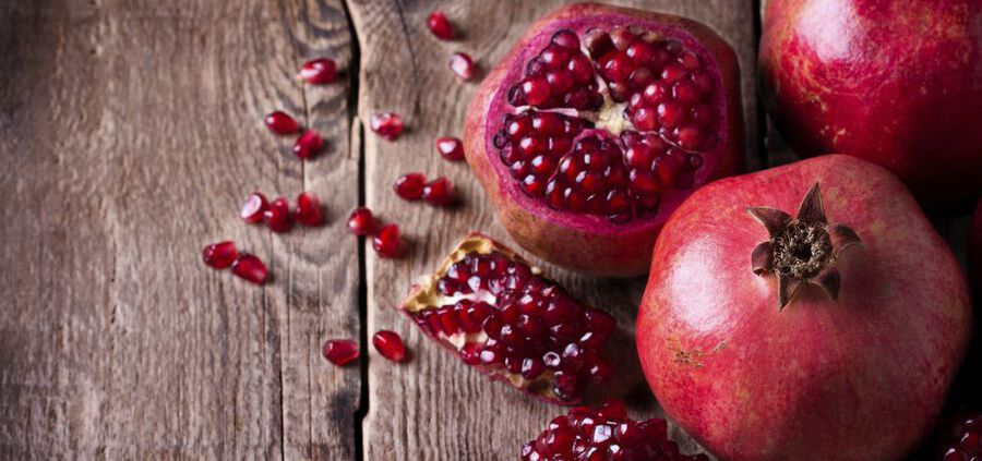 Some Red Pomegranates On Old Wooden Table