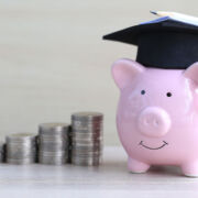 Graduation hat on pink piggy bank with stack of coins money on wooden background, Saving money for education concept Bildung Ausbildung Kosten Sparschwein Investition