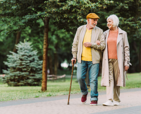 Senior couple smiling while walking on path in park